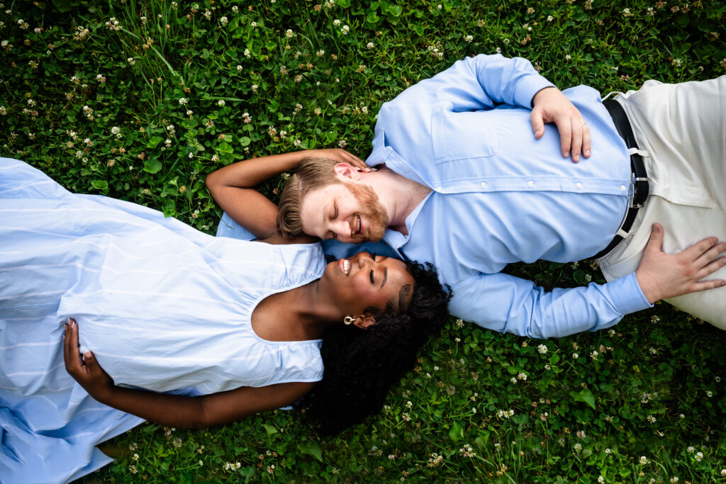 Expectant couple lying in a clover field in Bartram's Garden